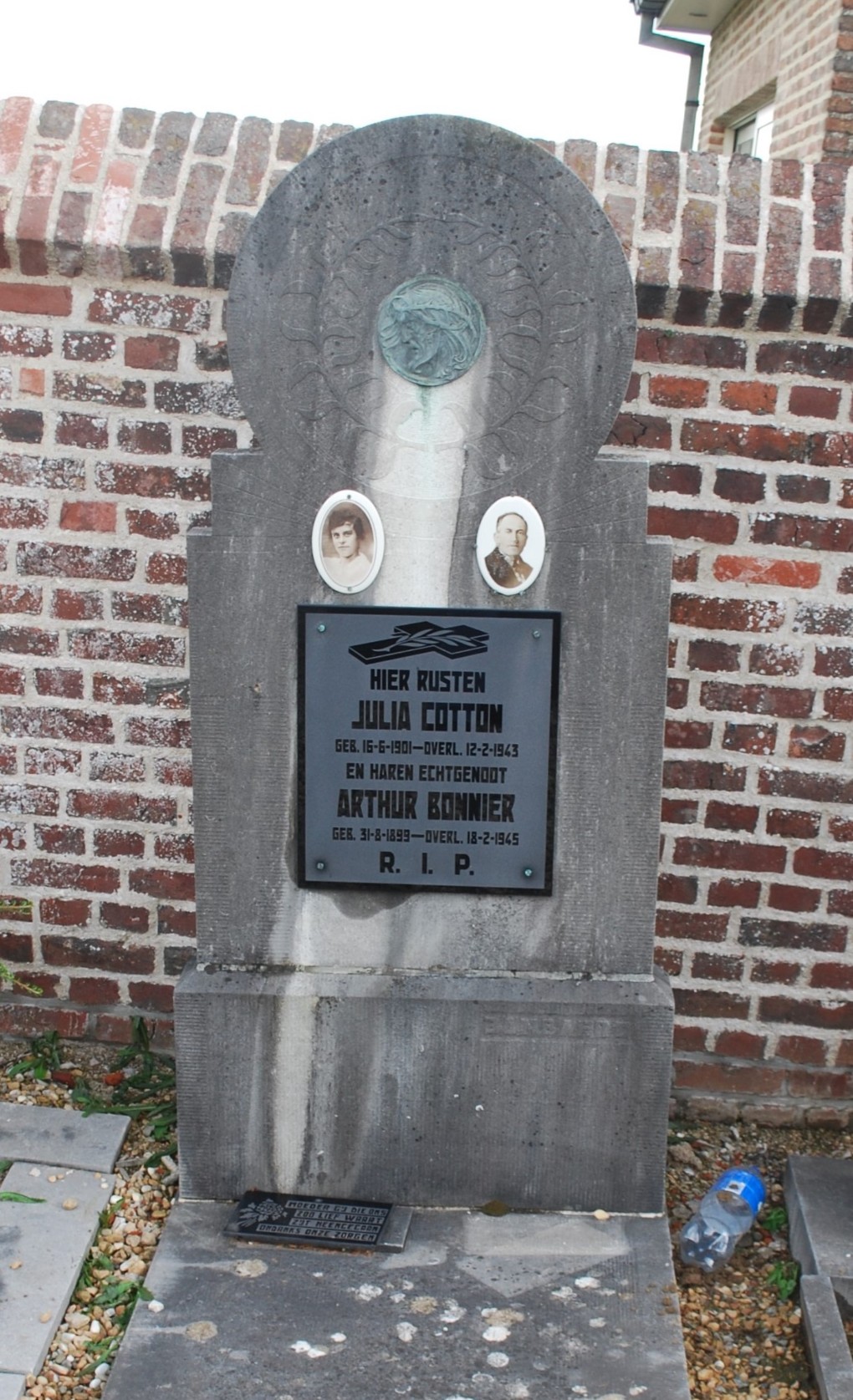 Grafsteen met foto's en tekst ter nagedachtenis aan Julia Cotton en Arthur Bonnier, tegen een bakstenen muur.