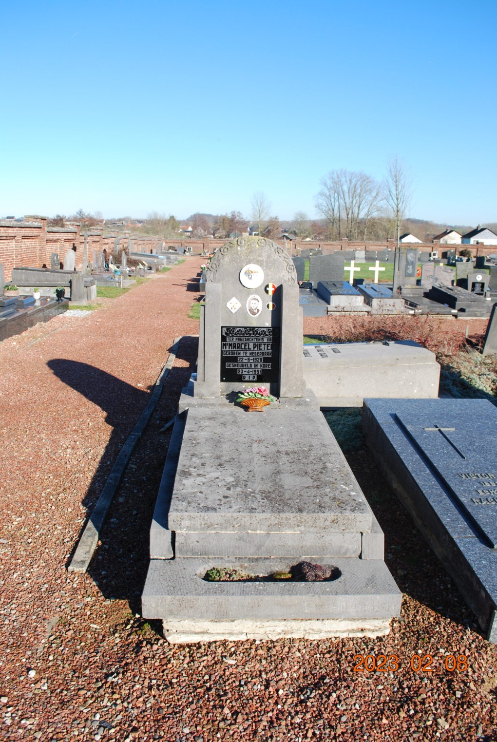 Grafsteen van Marcel Pieter op een begraafplaats met blauwe lucht en andere graven rondom.