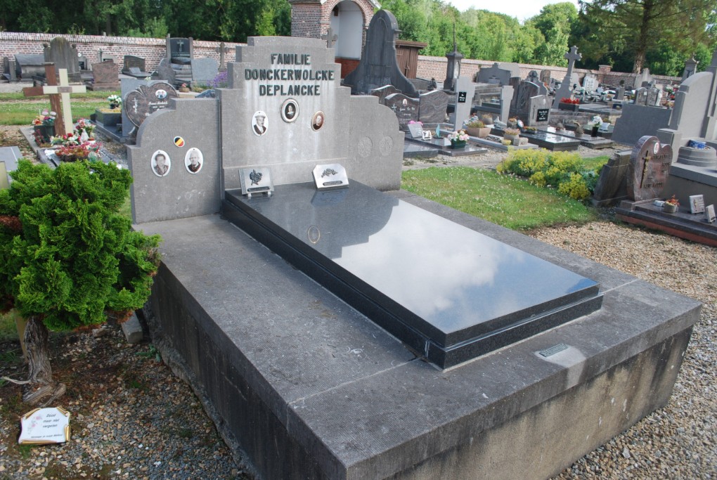 Grafsteen van familie Donckerwolcke Deplancke op een begraafplaats met omliggende graven en planten.