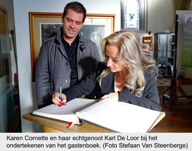 Vrouw tekent in gastenboek terwijl man toekijkt in een museumachtige ruimte.