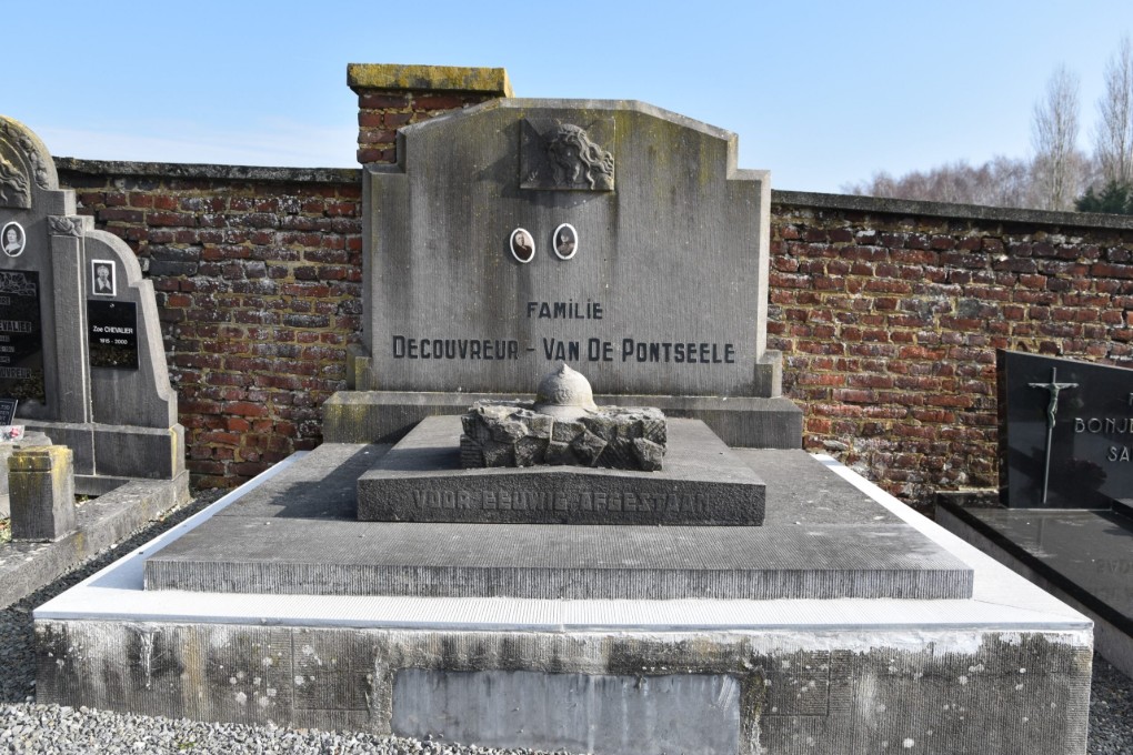Grafsteen van de familie Decouvreur - Van De Pontseele op een begraafplaats met een bakstenen muur op de achtergrond.