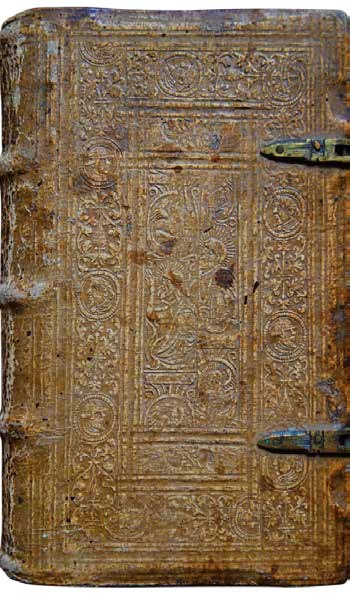 Oud leren boek met gedetailleerde reliëfversieringen en metalen sluitingen.