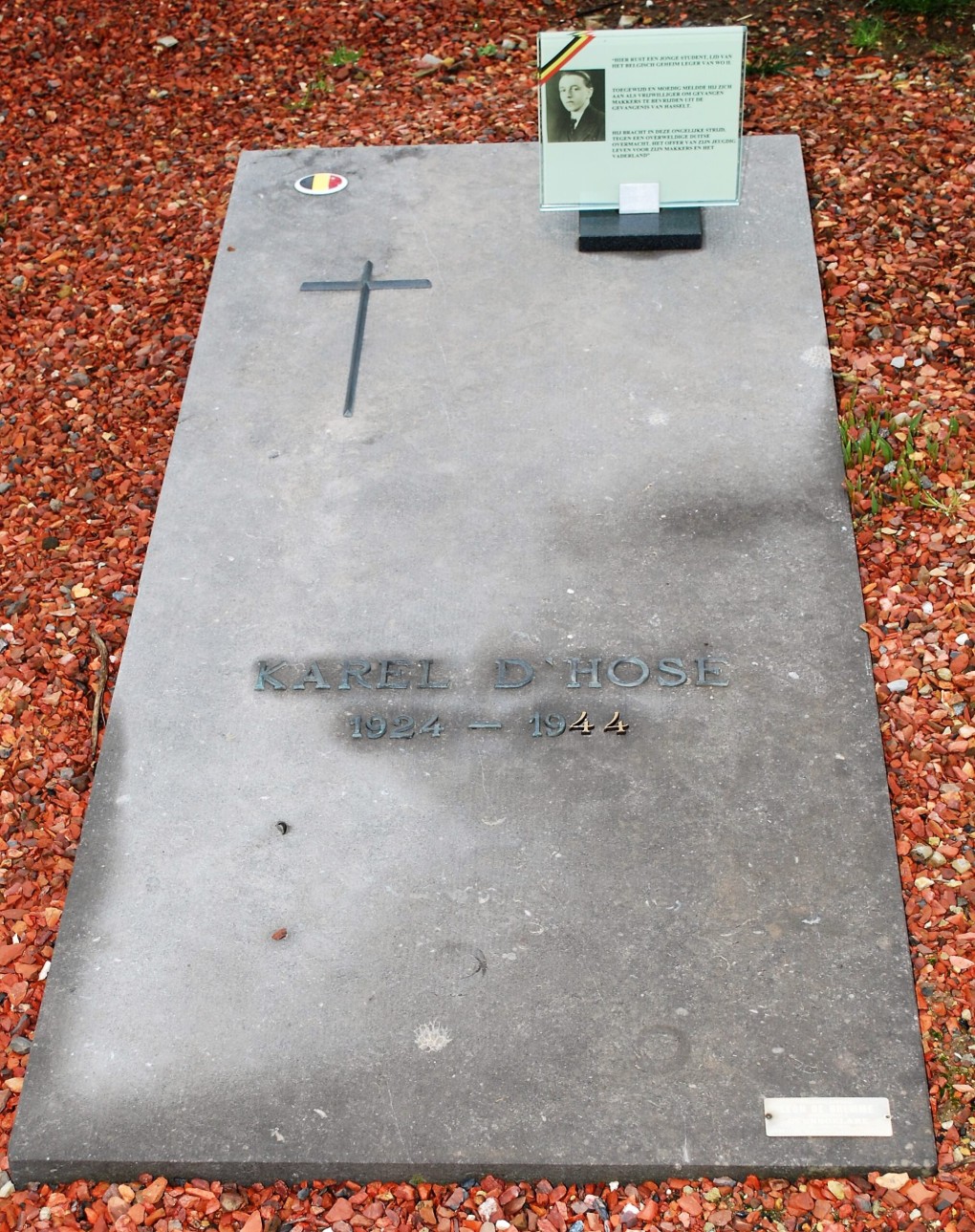 Grafsteen van Karel D'Hose (1924-1944) met kruis en Belgische vlag op rode steentjes.